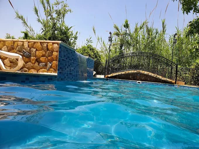 Aerial view of a private pool surrounded by pine and olive trees in Kfarmatta village, with the Damour valley and Mount Lebanon hills in the background.