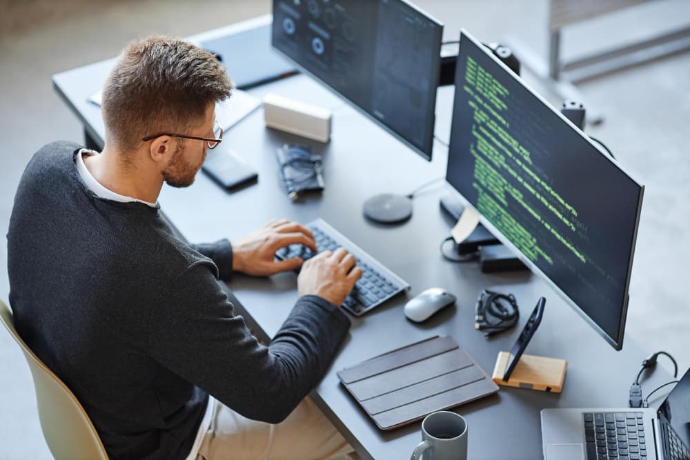 Software developers working on laptops in a modern Beirut office with the city skyline visible through the window