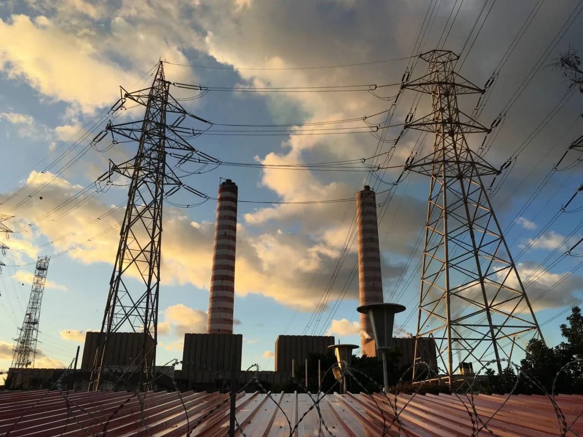 High-voltage electricity transmission towers and power lines running toward the Lebanon-Syria border under a clear sky