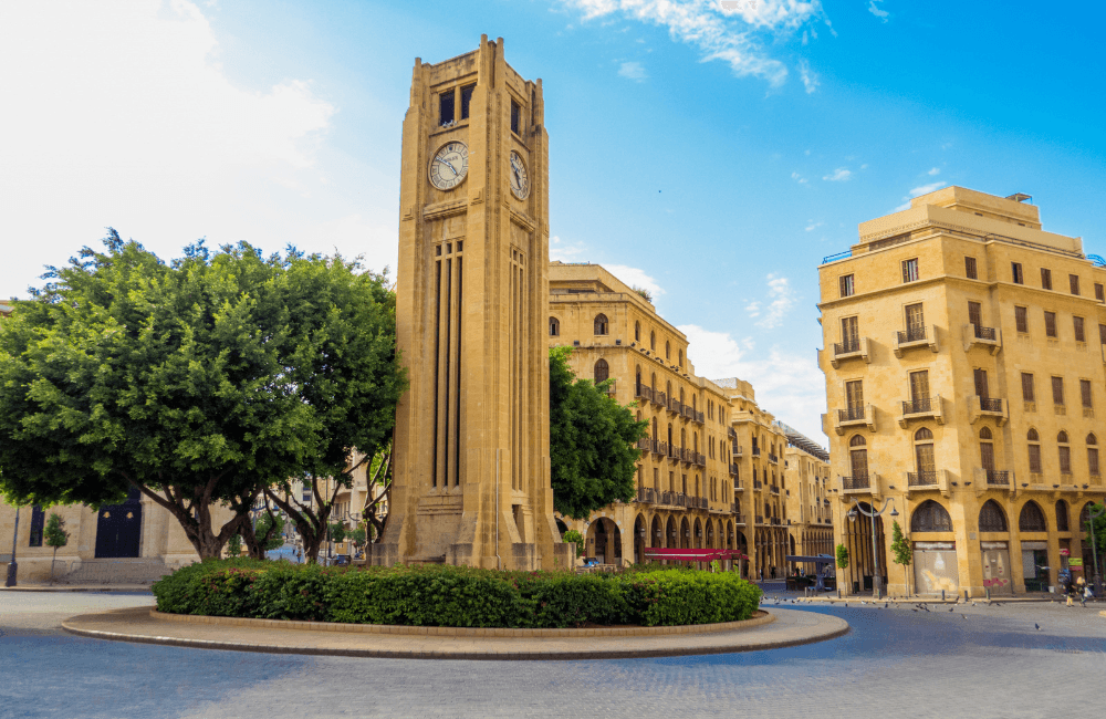 The clock tower at Nejmeh Square in Downtown Beirut, surrounded by restored sandstone buildings under a clear blue sky